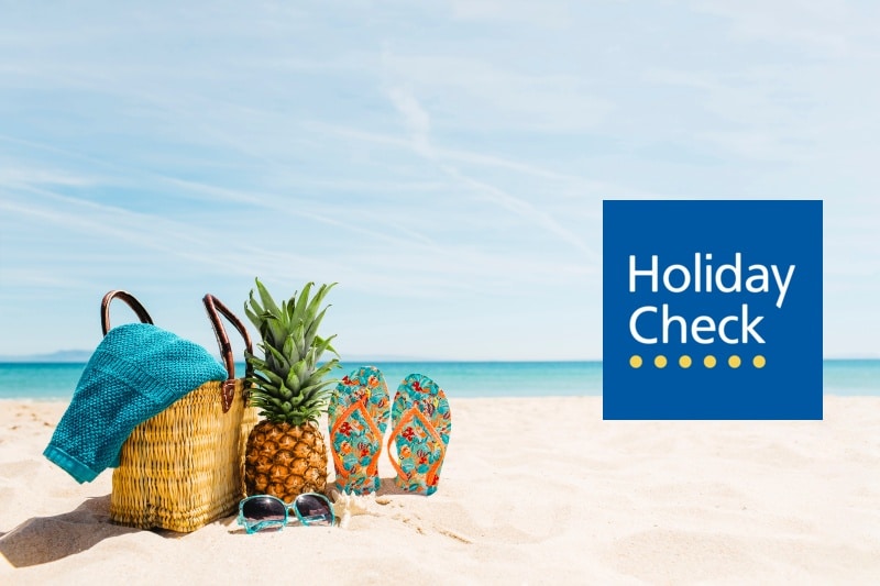 Logo HolidayCheck na tle plaży i morza